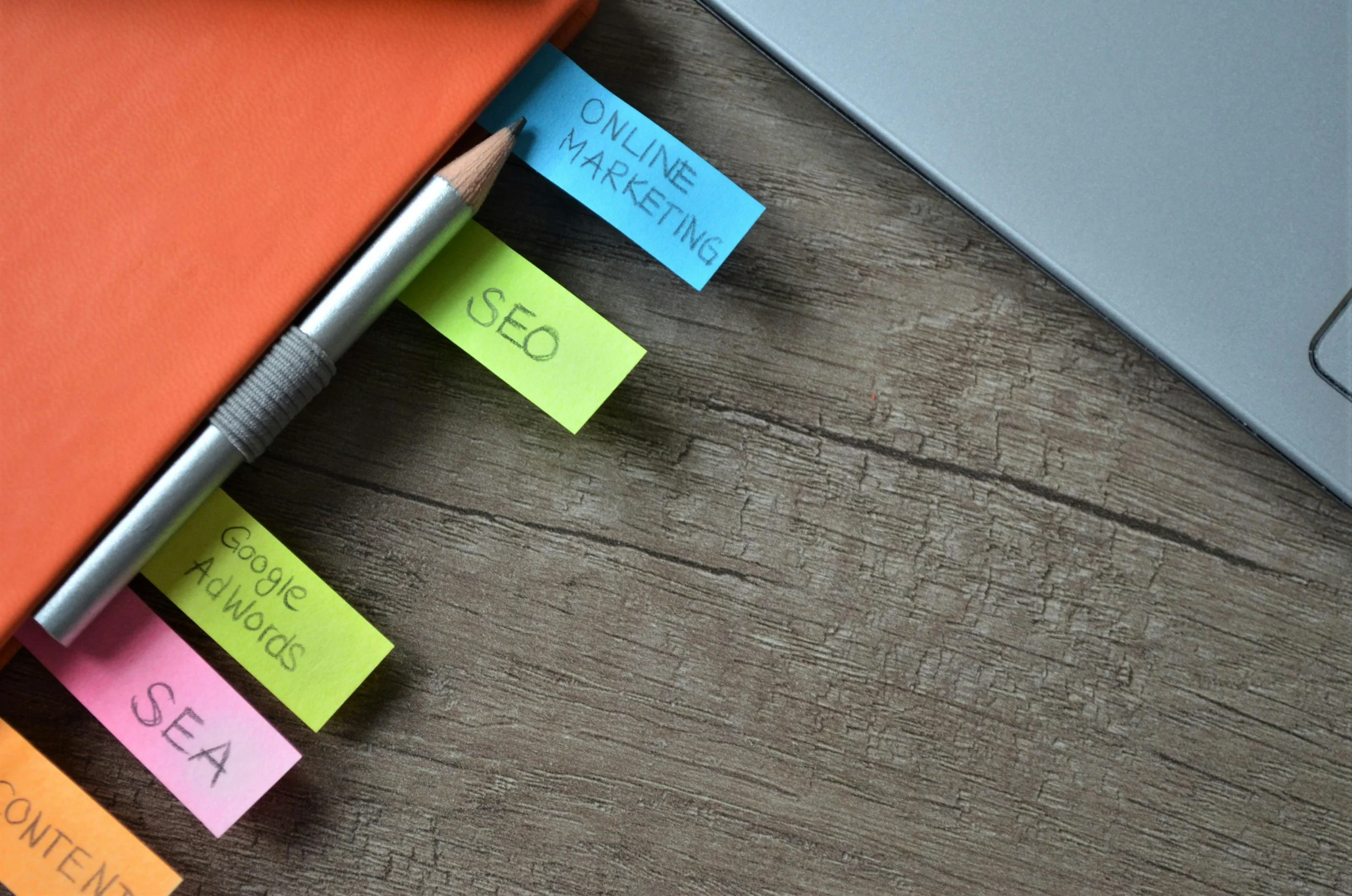 An orange notebook with brightly colored tabs focusing on online marketing such as SEO, Google AdWords, Ahrefs, etc.